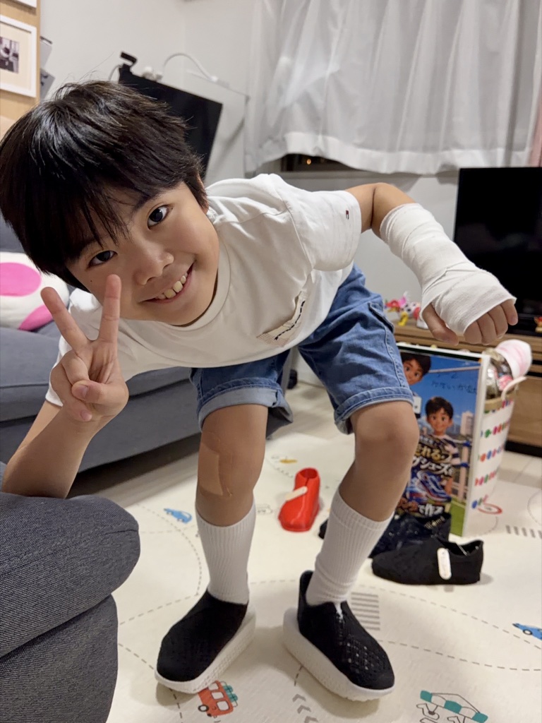 Kanata crouching in both finished K-Dash shoes, flashing a peace sign