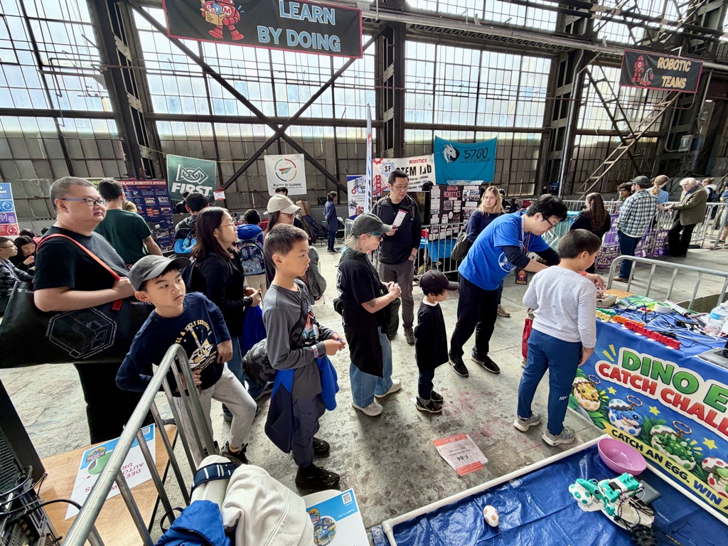Visitors lining up at the booth under the LEARN BY DOING banner