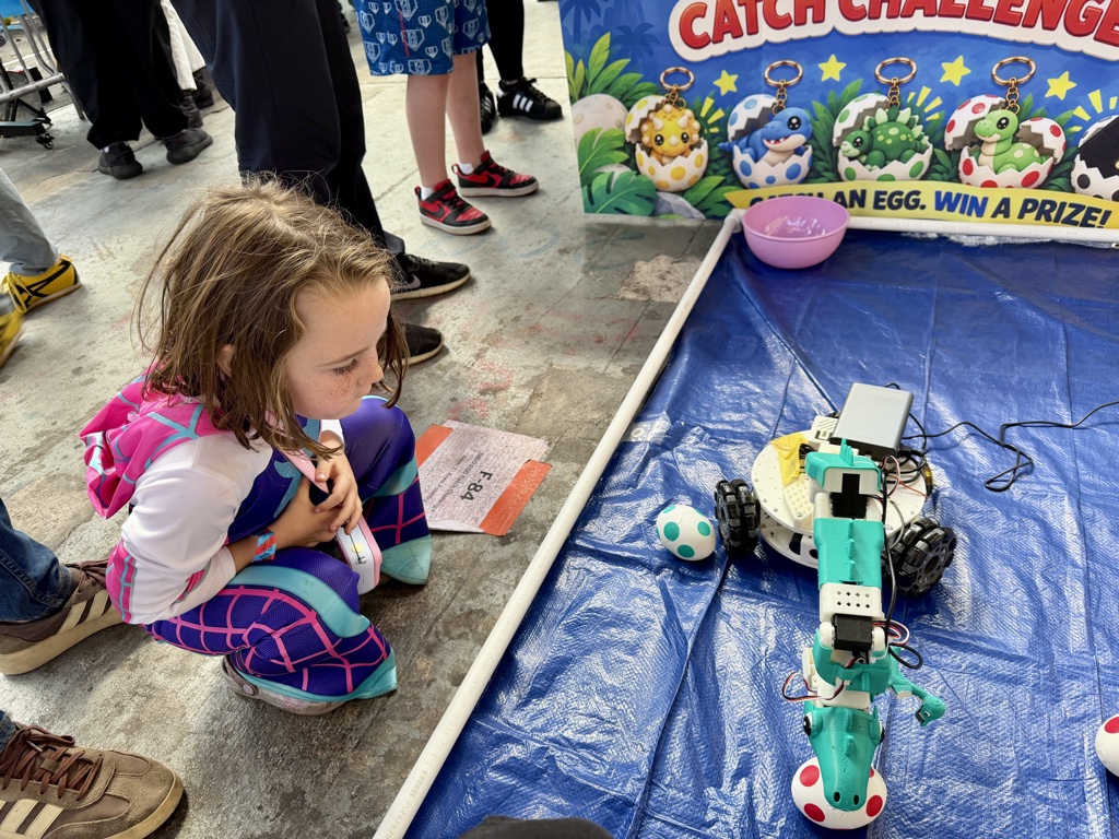 A young visitor watching the dinosaur robot pick up a spotted egg